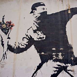 Banksy, Love is in the Air. Il gesto è quello della violenza, ma ciò che viene lanciato è un mazzo di fiori.
